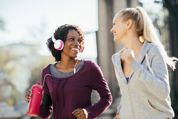 Two women jogging together with headphones in an urban park