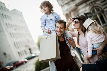 Joyful family with young child shopping and walking in the city