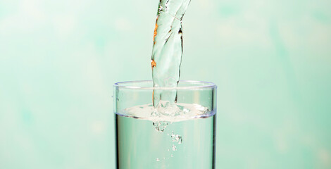 Splash in a glass, drop of water falling into a transparent glass, light background, selective focus