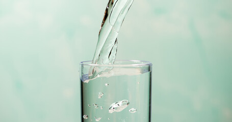Splash in a glass, drop of water falling into a transparent glass, light background, selective focus