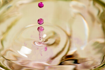 Splash in a glass, drop of violet liquid falling into a transparent glass, light background,...