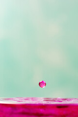 Splash in a glass, drop of violet liquid falling into a transparent glass, light background, selective focus