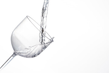Splash in glass, transparent glass receiving water, white background, selective focus