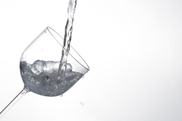 Splash in glass, transparent glass receiving water, white background, selective focus