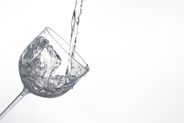 Splash in glass, transparent glass receiving water, white background, selective focus