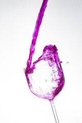 Splash in the glass, transparent glass receiving violet liquid, white background, selective focus