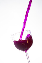 Splash in the glass, transparent glass receiving violet liquid, white background, selective focus