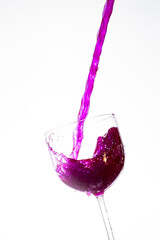 Splash in the glass, transparent glass receiving violet liquid, white background, selective focus