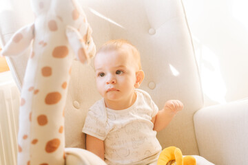 Portrait of a nine month old baby with a stuffed giraffe sitting in a rocking chair