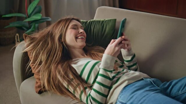 Happy girl falling couch making smartphone selfie closeup. Woman using cellphone