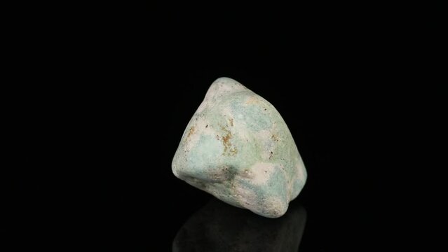 Polished mineral stone zoisite rotates in a circle on a black background