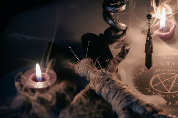 A haunting occult setup featuring a pendulum, mystical symbols, candles, a voodoo doll, and a...