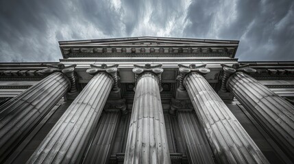 An artistic depiction of classical columns against a dramatic cloudscape in greyscale tones
