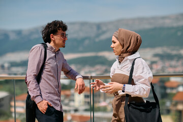 After a day at the office, a business man engages in conversation with his Muslim colleague wearing...