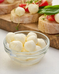 Mozzarella balls in glass bowl on a white background