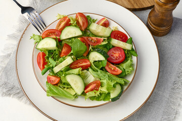 Salad of chopped cherry tomatoes and cucumbers in a white round plate on the table, healthy food