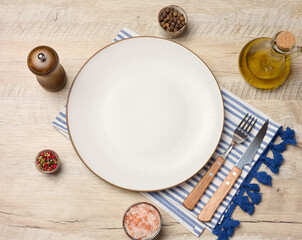 Empty round white plate, olive oil, spices on wooden table