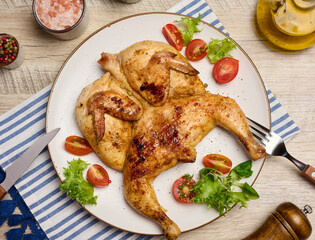 Whole fried chicken with spices in a white round plate on the table