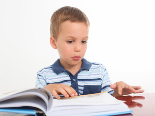 studio portrait of a confused little boy reeding a book