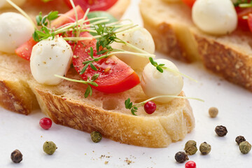 Round mozzarella, cherry tomatoes and microgreens on a piece of white bread, a healthy sandwich