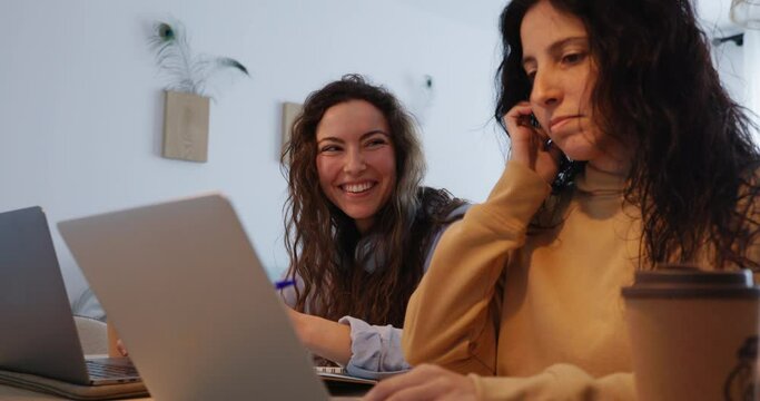 coworkers laughing while working at home with their laptops