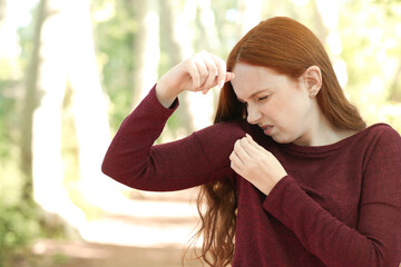 Woman with long hair who sweats smells her armpit