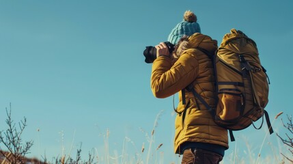 A focused individual in winter clothing captures the cold beauty of a wintery scene under the bright day's sky