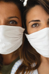 Closeup of two young women face to face looking at camera with protective face mask during...