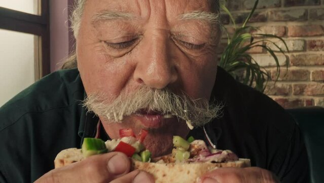 Elderly man with a moustache eating
