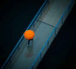 aerial view of a person walking on a bridge with an umbrella