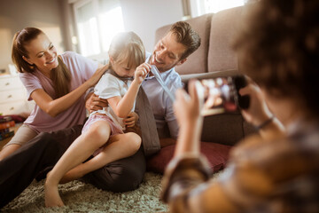 Family playing together on living room floor while being photographed