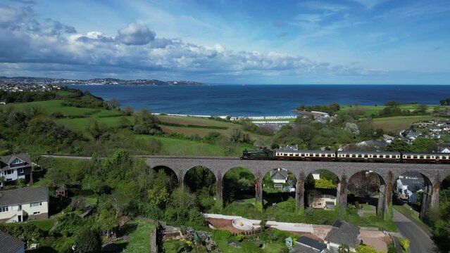 Broadsands, South Devon, England: DRONE VIEWS: A steam train heading for Paignton crosses a viaduct. The Torbay Steam Railway line is a major attraction for day-trippers, tourists and holidaymakers.