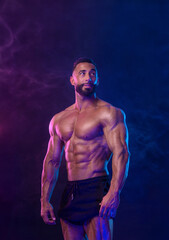Fototapeta na wymiar Athlete bodybuilder in neon colors. Fit man posing on black background. Sports concept. Bodybuilding competition. Download, high resolution, photo.