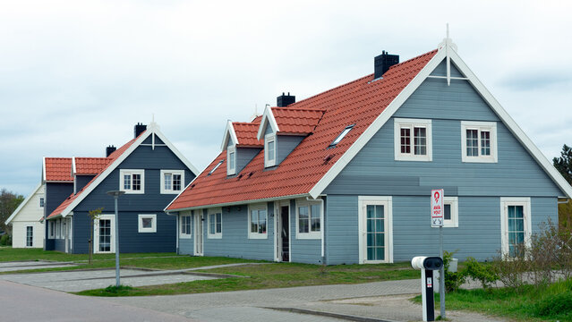 2024-04-23, Julianadorp aan Zee, Nordholland, Niederlande, Strandnahe Ferienh&auml;user in dem Landal Beach Resort Ooghduyne, Ansicht von vorne mit Gartenarbeiter