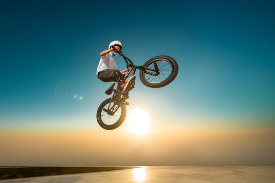 A teenager BMX Racing Rider performs tricks in a skate park on a pump track.