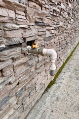 Outdoor faucet water tap with white PVC pipe and reed valve on light brick wall background texture. Copy space, water saving concept