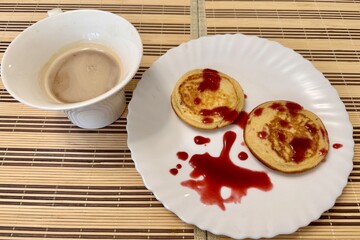 Healthy fritters with with lingonberry jam on a white ceramic plate next to white cup of coffee. Vegan breakfast food at the restaurant