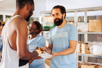 Portrait of male charity worker distributing free food to the needy and homeless people. At...