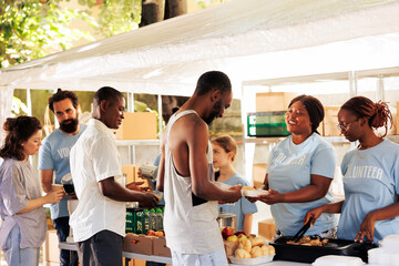 Outdoor food distribution event orchestrated by non-profit, attracting individuals of all races,...