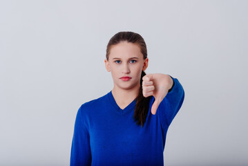 young caucasian serious looking woman in blue sweatshirt showing thumb down gesture, dont like it,...