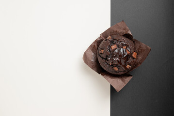 A chocolate muffin is sitting on a white background