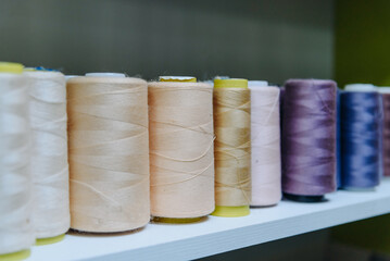 amount of different large skeins of threads on special shelves in sewing studio or atelier, several...