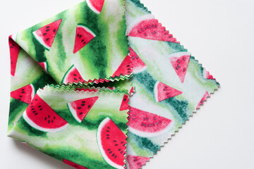 folded fabric with watermelon prints and serrated edges on blank paper