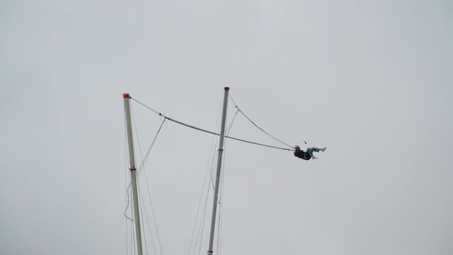 The daring individual, loving thrills and adrenaline, attaches to the Tarzan rope and gets catapulted high into the air against a backdrop of thick clouds.