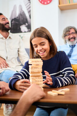 Vertical. Happy diverse generation family gathered playing Jenga at home. Caucasian people together...