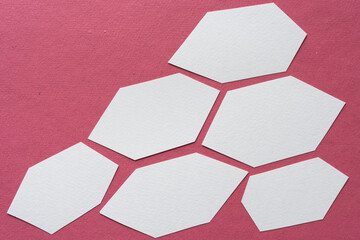 roughly cut hexagonal paper shapes arranged on pink paper