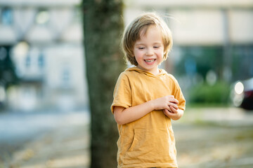 Funny little boy having fun in the city on sunny summer day. Outdoor summer activities for kids.