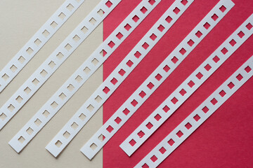 blank white and red construction paper and coil binding edge strips arranged diagonally