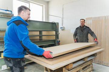 Naklejka na ściany i meble carpenters carrying wooden panel in workshop. High quality photo