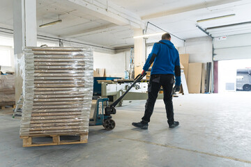 man worker taking wooden pieces out of the factory to load a van, manufacture. High quality photo